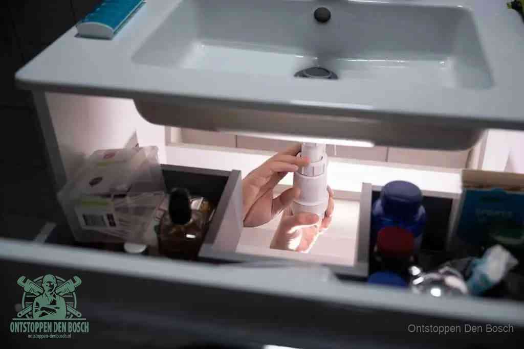 Een pompfles met zeep boven een wastafel, de heet water en afwasmiddel-methode om een vetprop in de afvoer los te maken in Den Bosch