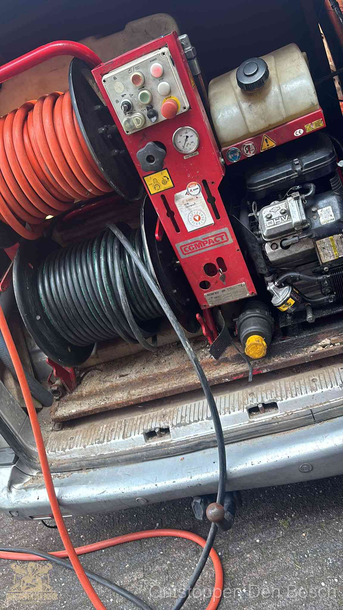 Een rood hogedruk-rioolreinigingstoestel met slangen in de laadbak van de bedrijfsbus, apparatuur voor een hardnekkige wc-verstopping in Den Bosch