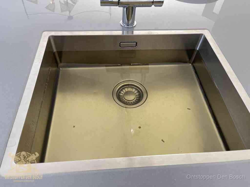 Stilstaand water in een rvs spoelbak dat niet wegloopt, een duidelijk signaal van een gootsteenverstopping in Den Bosch
