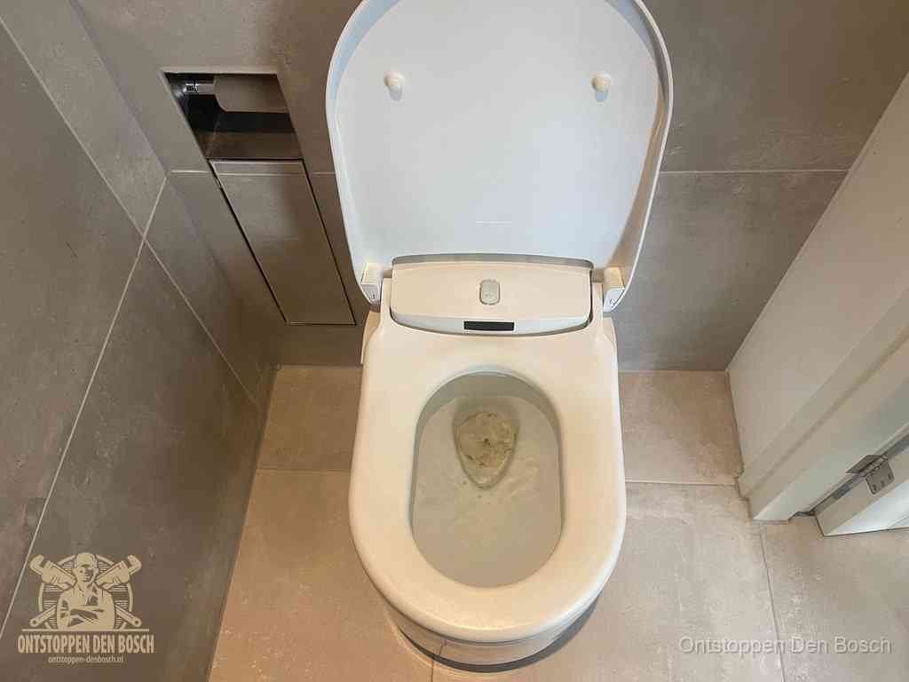 Een wit hangtoilet waarin een prop wc-papier op het water blijft drijven, een duidelijk signaal van een verstopte wc in Den Bosch