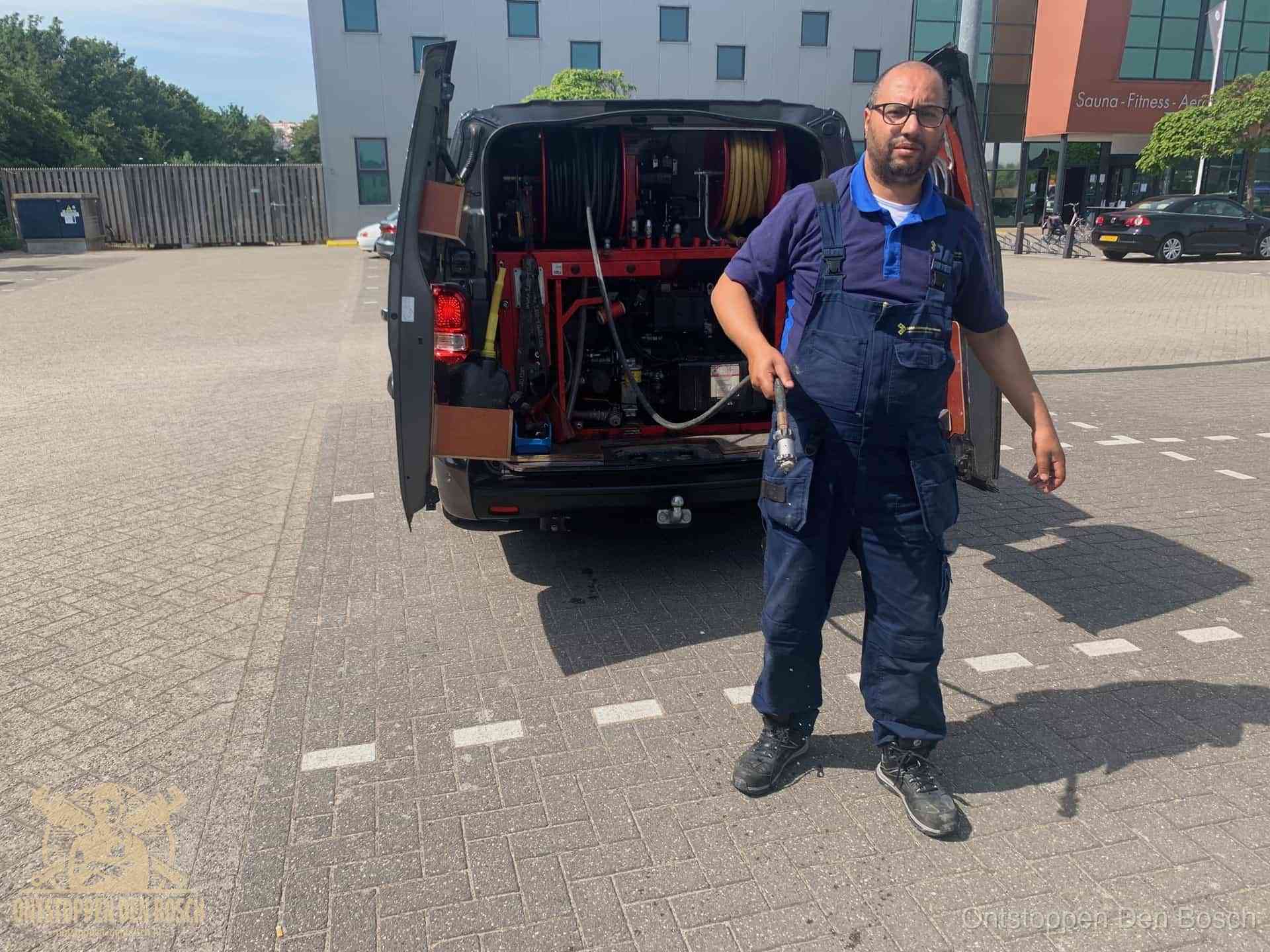 Een monteur bij zijn bestelbus met een hogedruk- en rioolreinigingsunit, klaar om de oorzaak van terugkerende wc-verstoppingen aan te pakken in Den Bosch