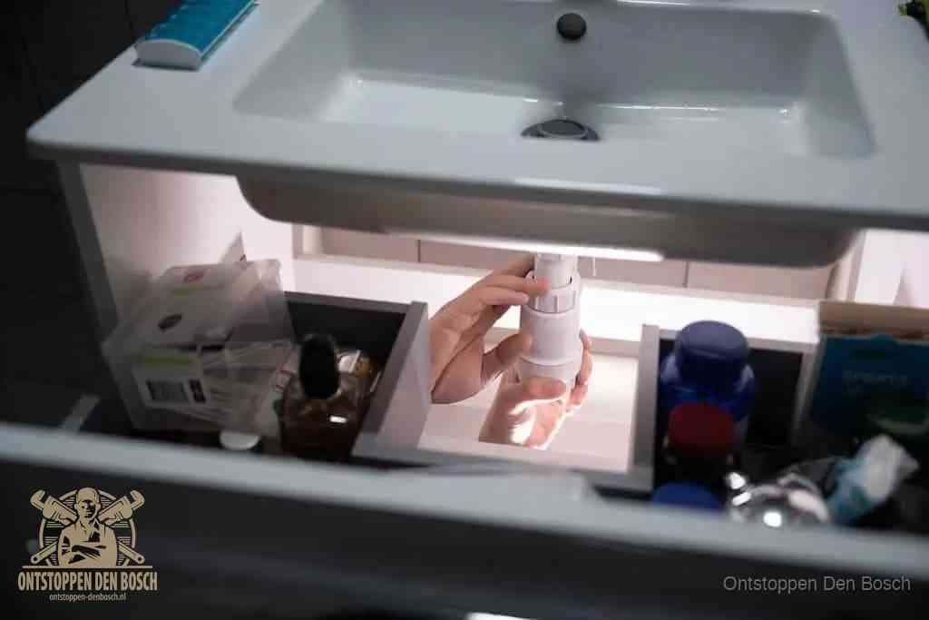 Een pompfles met zeep boven een wastafel in de toiletruimte, de warm water en afwasmiddel-methode om de wc te ontstoppen in Den Bosch
