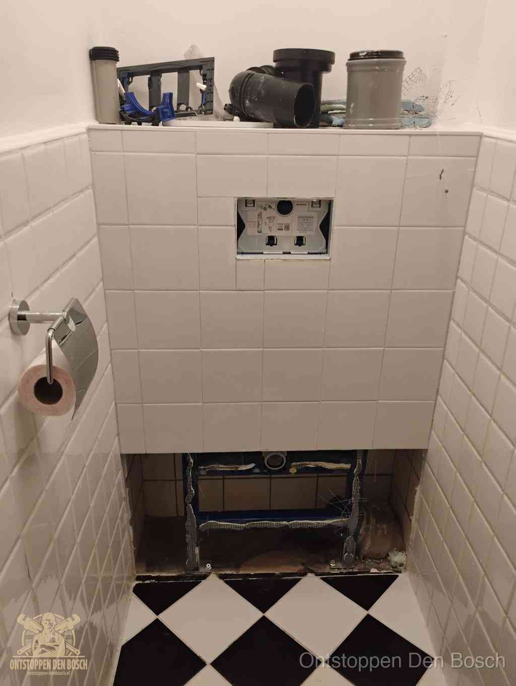 Een toiletruimte waar het hangtoilet en de inbouwreservoir-onderdelen zijn vrijgelegd voor onderhoud, periodiek nazicht voorkomt een wc-verstopping in Den Bosch